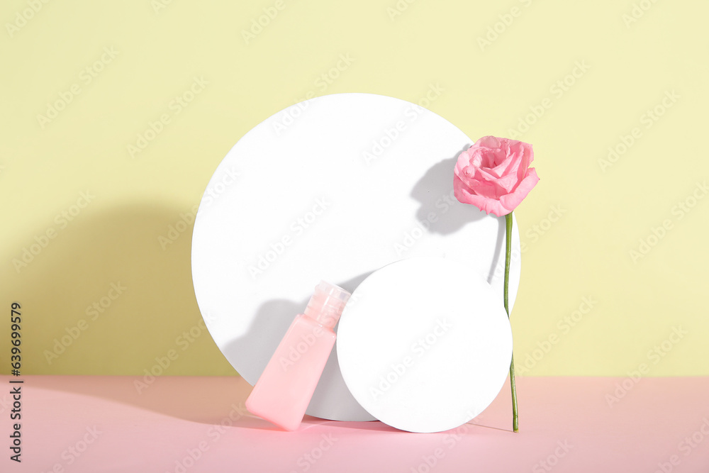 Composition with bottle of cosmetic product, plaster podiums and rose flower on color background