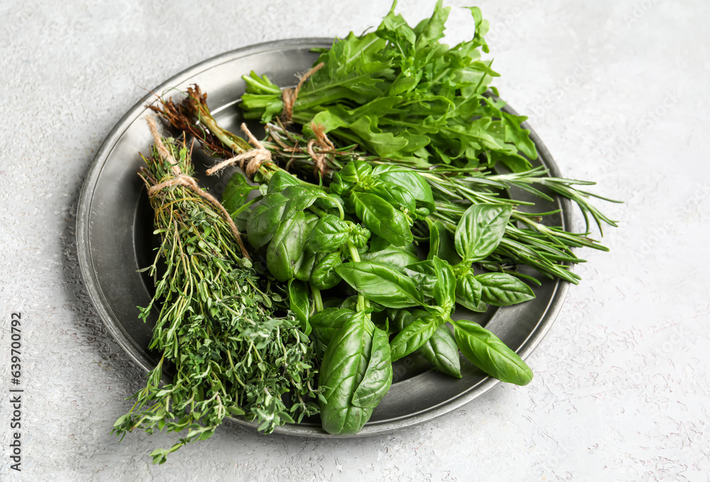 Plate with fresh aromatic herbs on light background