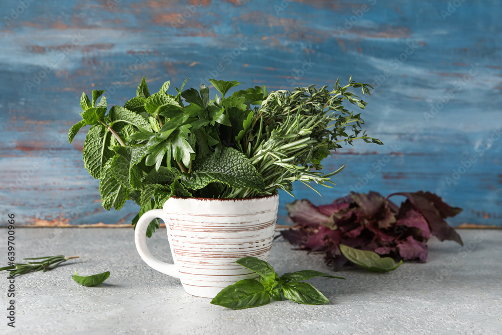 Cup with fresh aromatic herbs on table