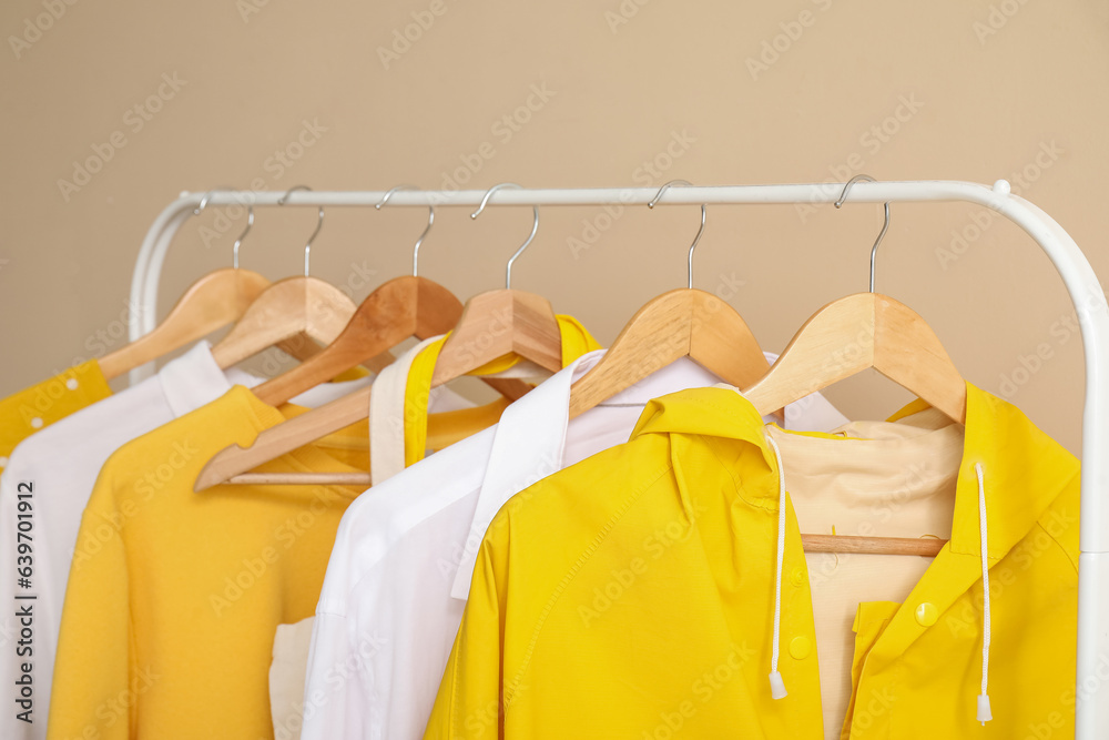 Colorful clothes hanging on rack near color wall, closeup