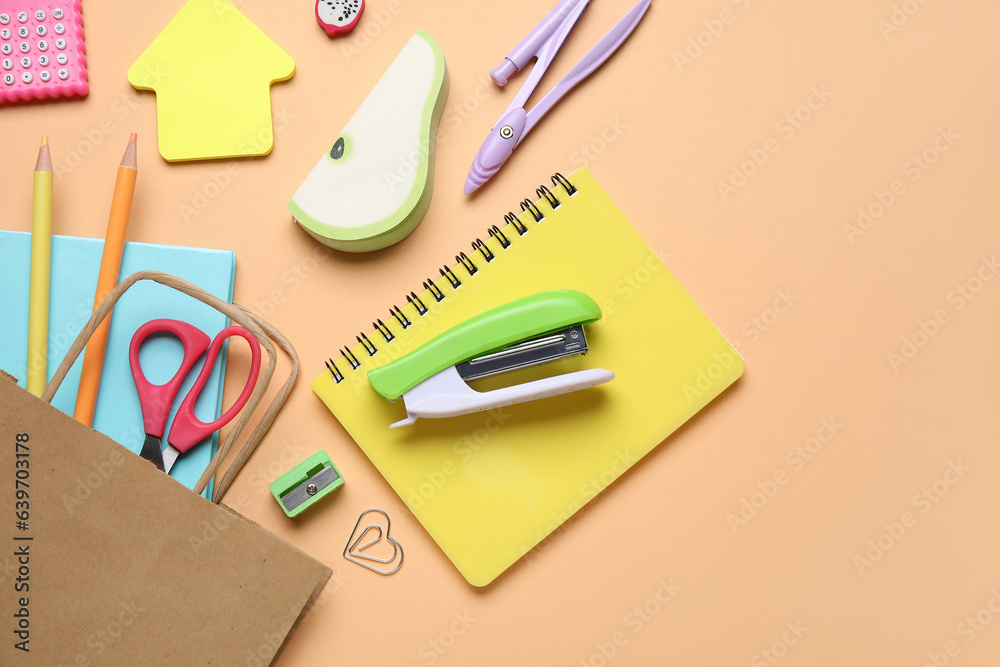 Paper bag with different stationery on color background, closeup