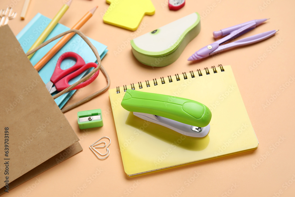 Paper bag with different stationery on color background, closeup