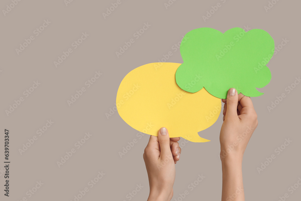 Female hands with speech bubbles on grey background