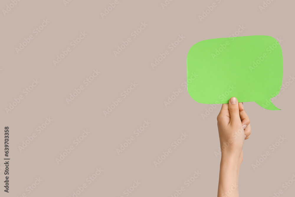 Female hand with speech bubble on grey background