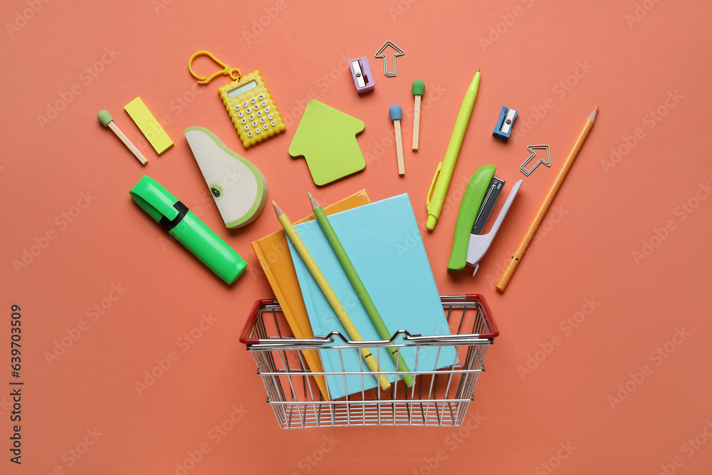 Shopping basket with different school stationery on orange background