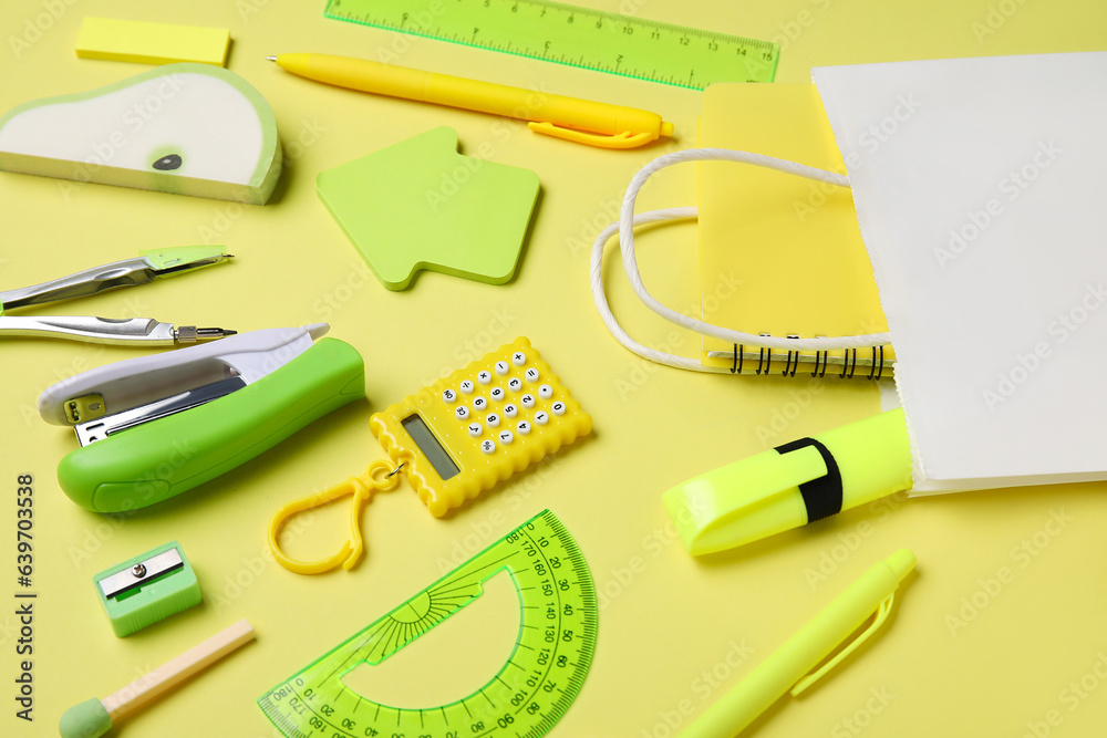 Shopping bag with different school stationery on yellow background, closeup