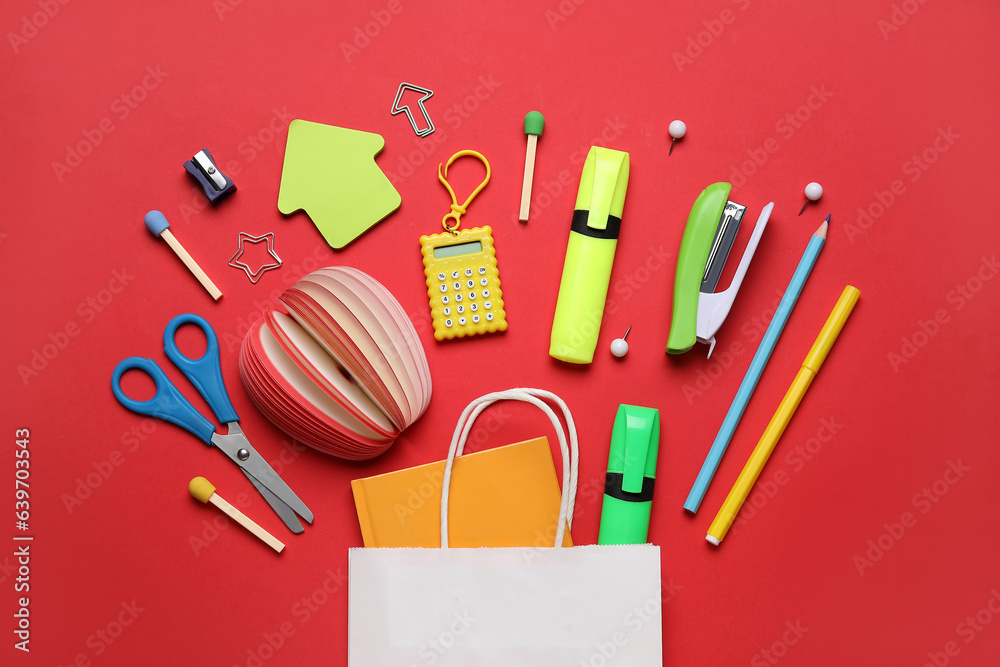 Shopping bag with different school stationery on red background