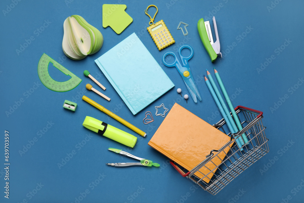 Shopping basket with different school stationery on blue background