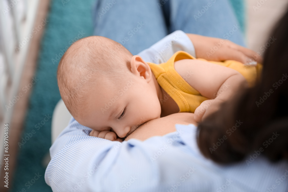 Young woman breastfeeding her baby in bedroom, closeup