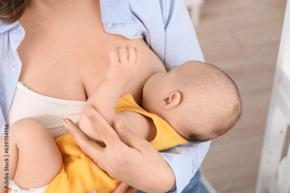 Young woman breastfeeding her baby in bedroom, closeup