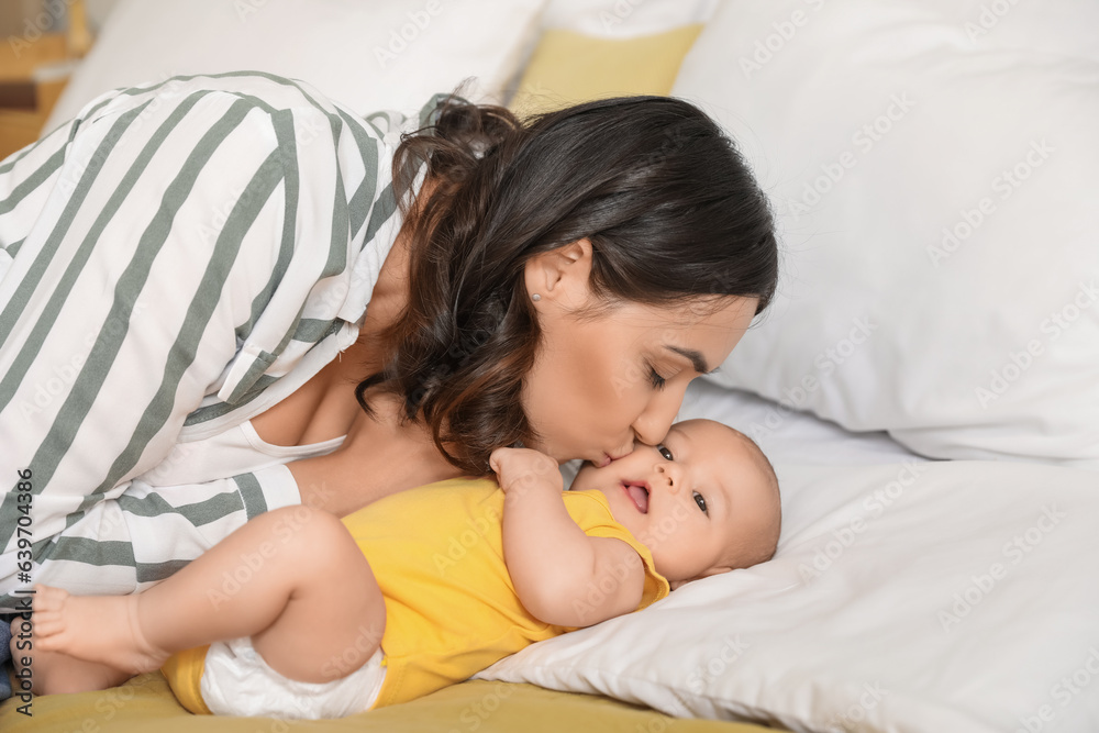 Young woman kissing her baby in bedroom