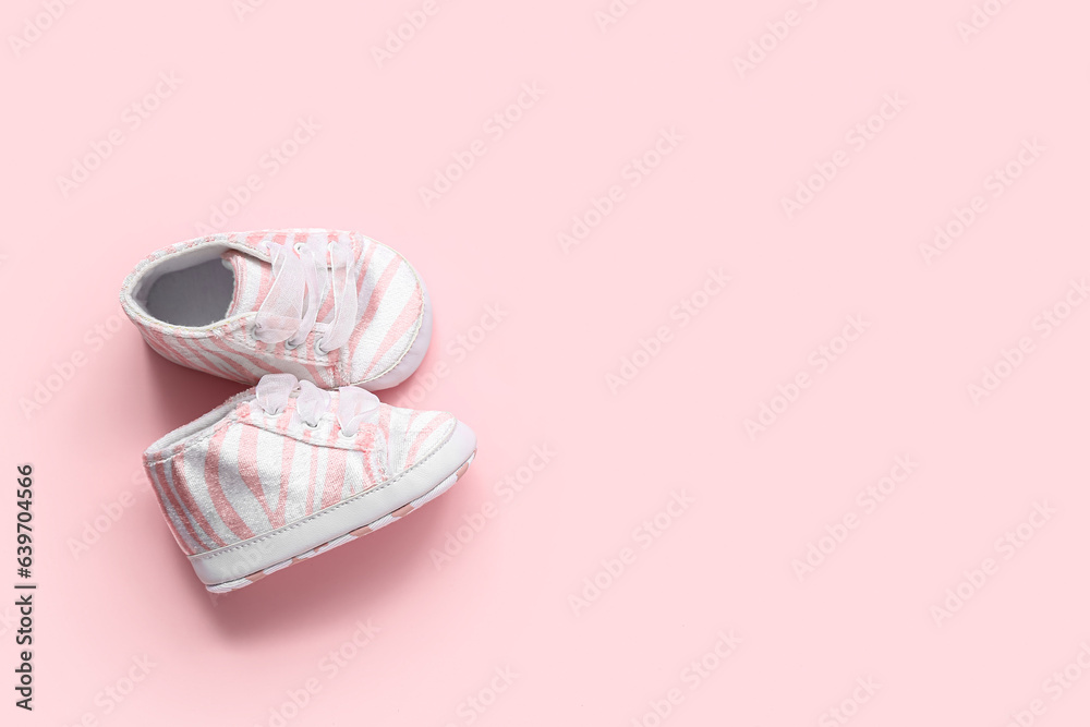 Stylish baby booties on pink background