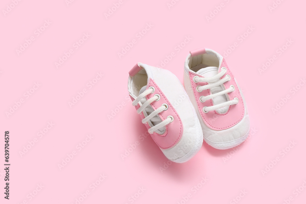 Stylish baby booties on pink background