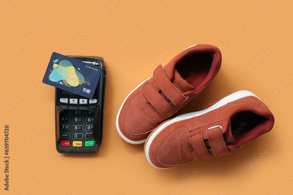 Pair of stylish childs shoes, payment terminal and credit card on color background