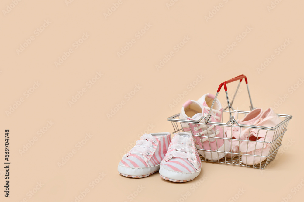 Shopping basket with baby booties on color background