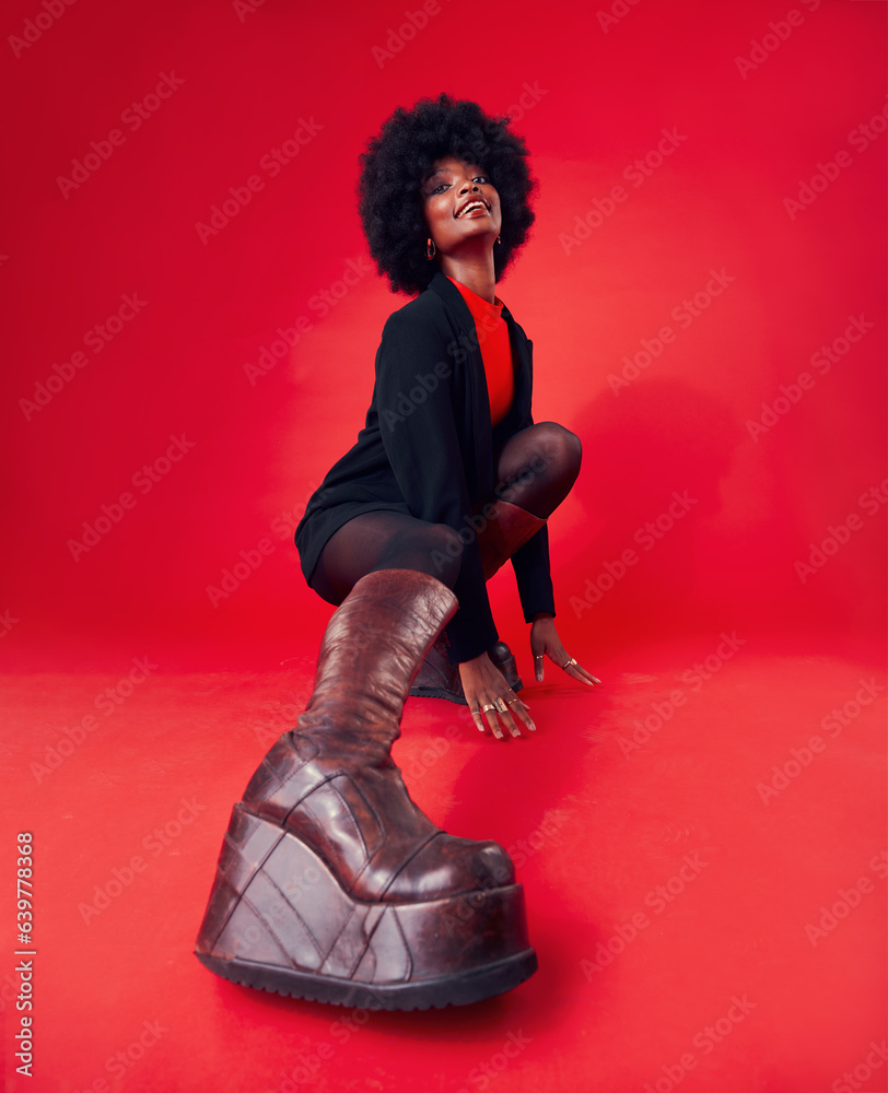 Fashion, boots and portrait of a black woman on a red background in studio to model trendy footwear.