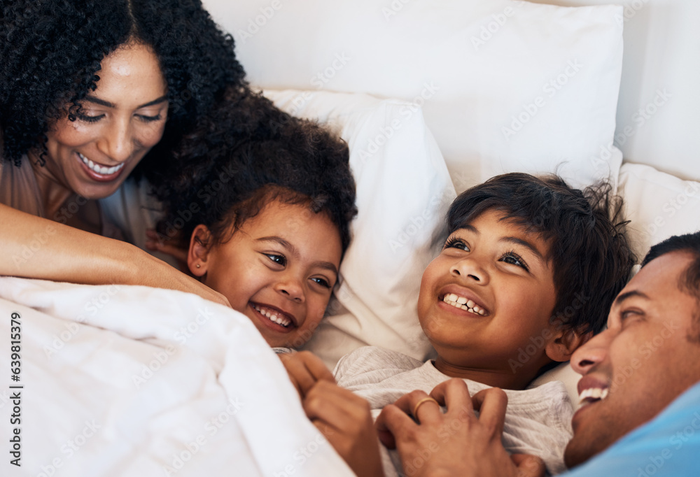 Family, funny and children laughing in bed at home in the morning together with their happy parents.