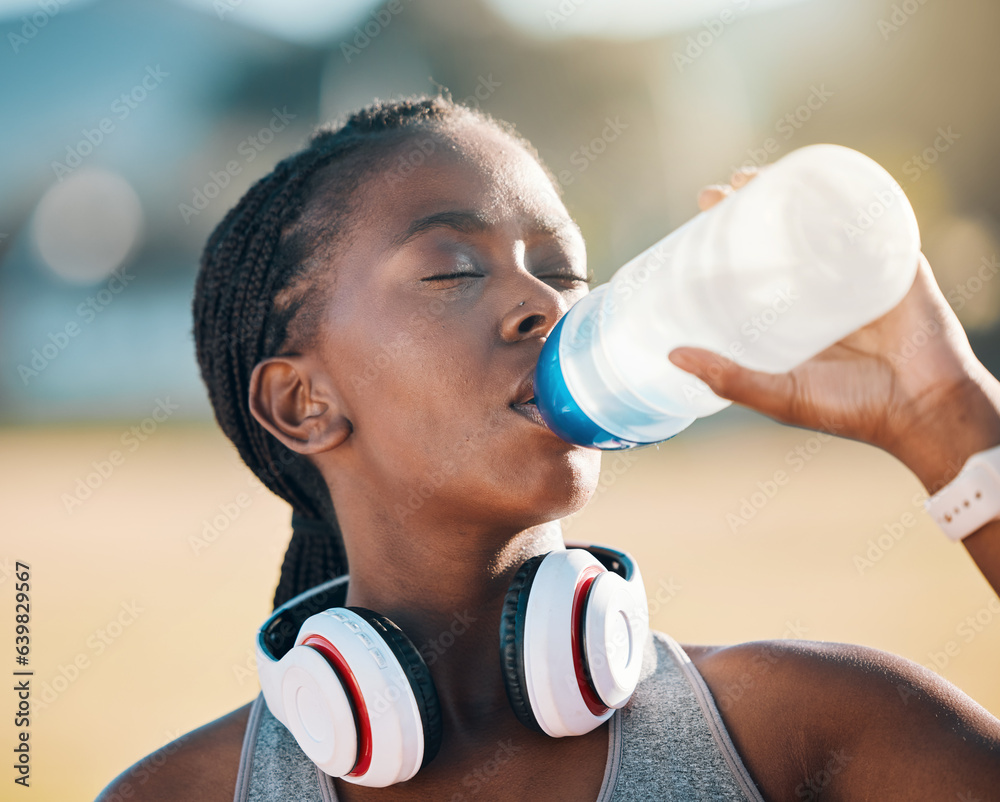 Black woman, drinking water and health, fitness and runner outdoor with headphones, thirsty after wo