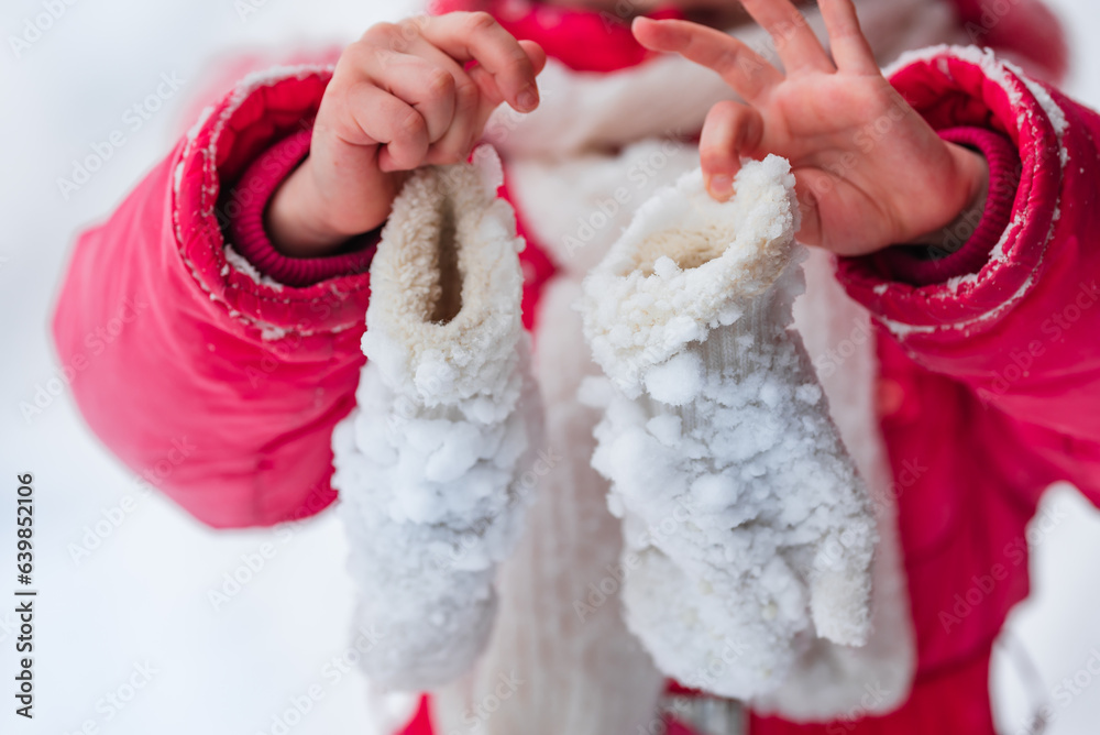 Frozen, icy baby mittens in the childs hands. Angina, cold, hypothermia.