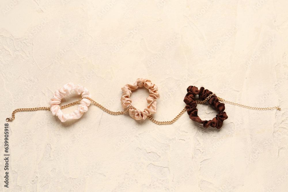 Set of silk scrunchies and necklace on light background