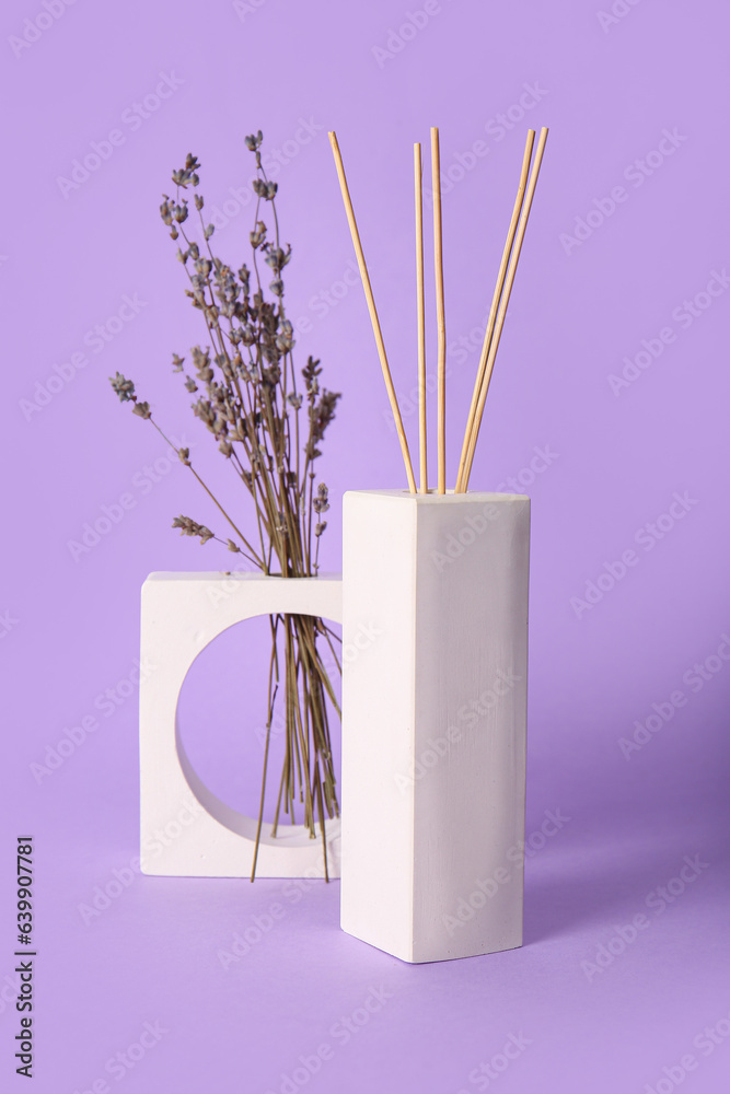 Floral reed diffuser and lavender flowers on purple background