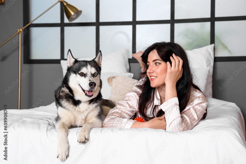 Young woman with her Husky dog in bedroom