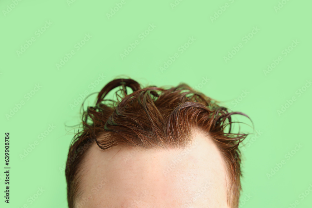 Young man with wet hair on green background