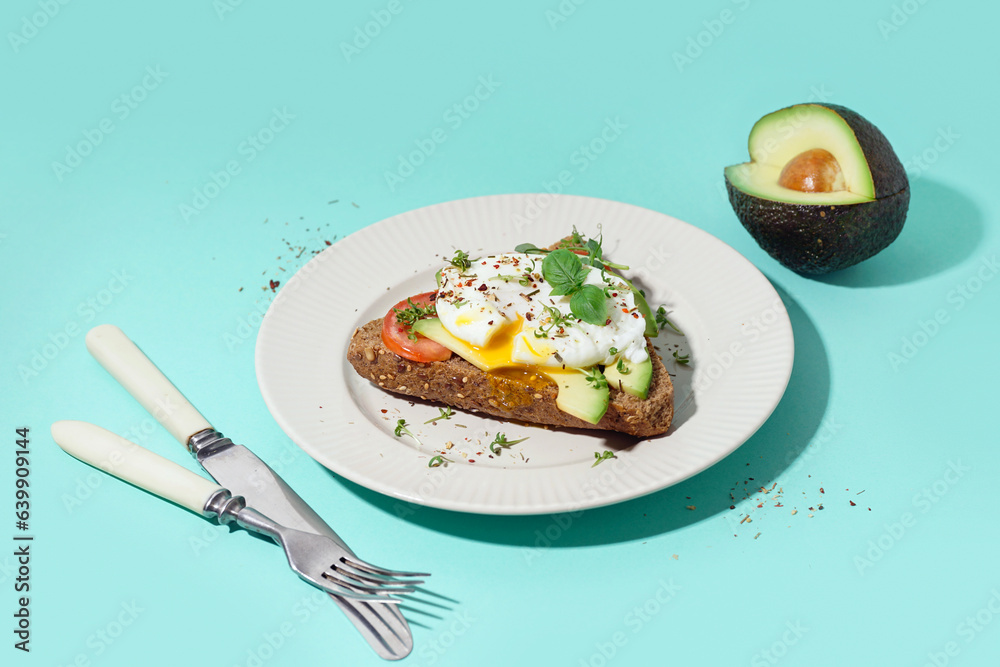 Plate of tasty sandwich with egg on blue background