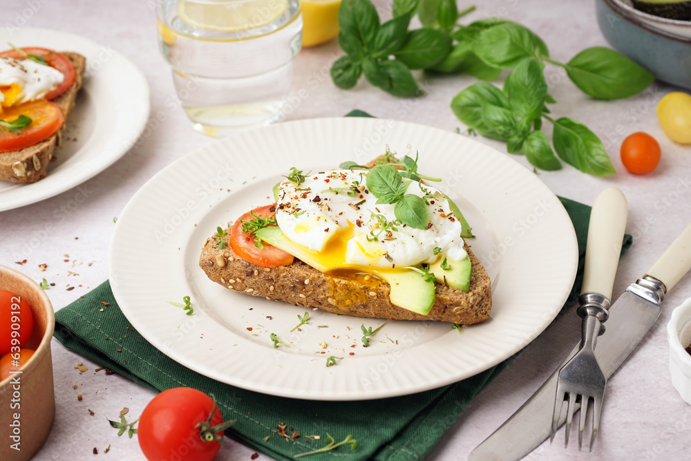 Plate of tasty sandwich with egg on light background