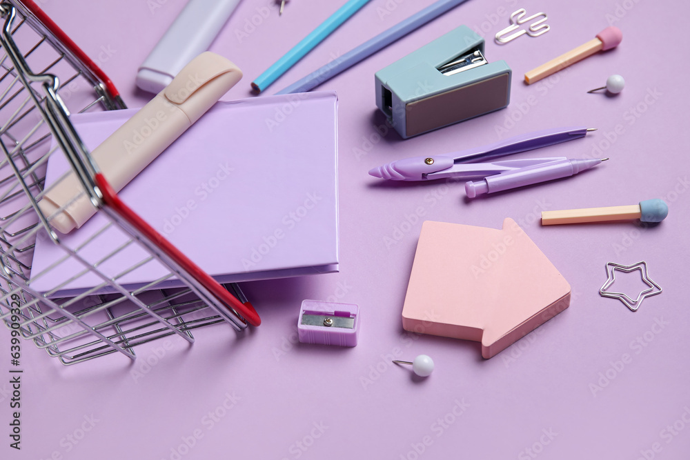 Composition with shopping basket and different stationery on lilac background