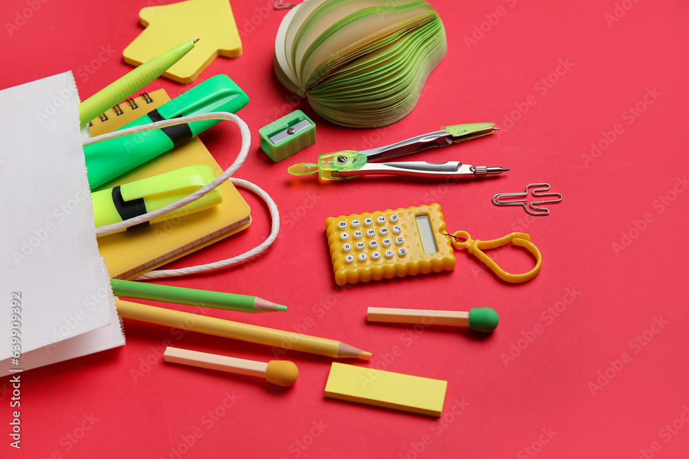 Composition with paper bag and different stationery on red background