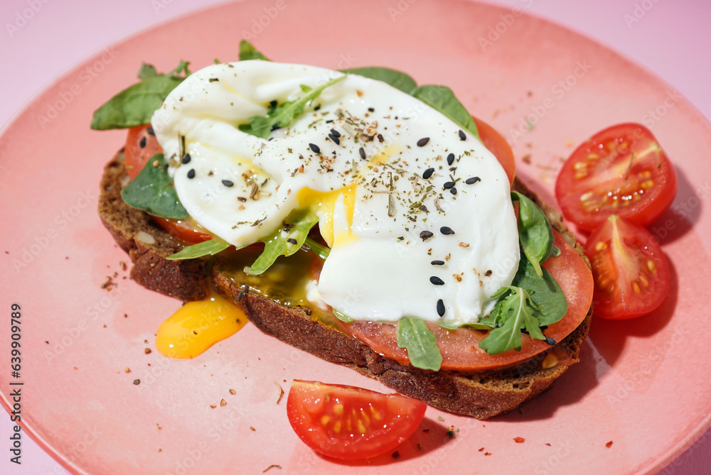 Plate of tasty sandwich with egg on pink background