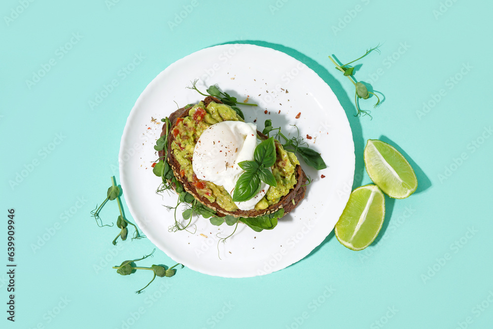 Plate of tasty sandwich with egg on turquoise background