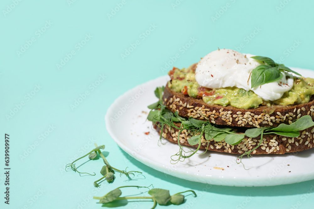 Plate of tasty sandwich with egg on turquoise background