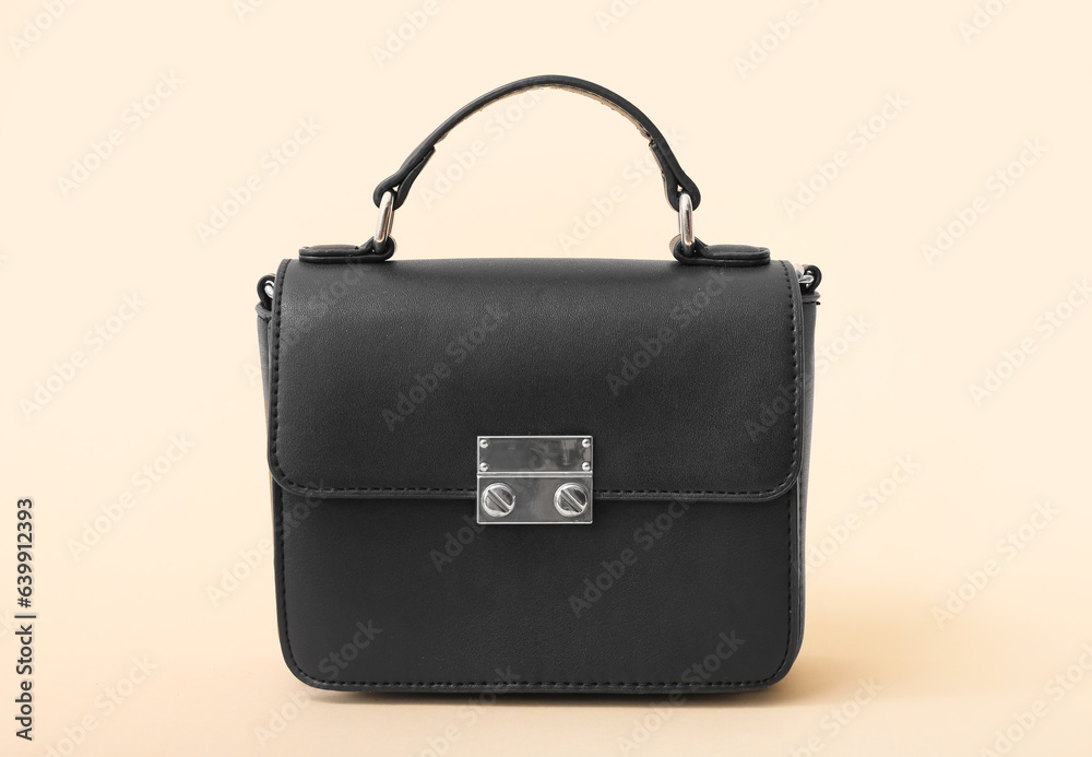 Stylish black handbag on beige background