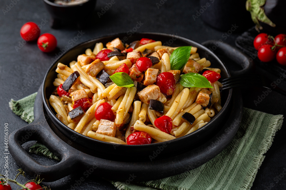 Sicilian pasta, casarecce with swordfish, tomato, and eggplant. Decorated with basil leaves. Dark ta