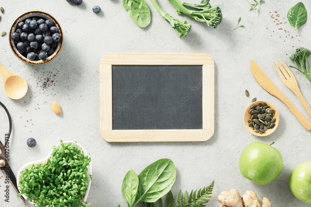 Vegetarian vegan healthy ingredients and empty chalk board on grey stone background