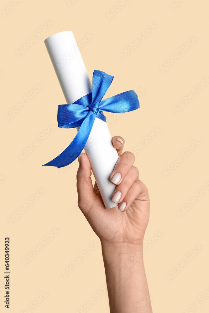 Woman holding diploma with ribbon on yellow background