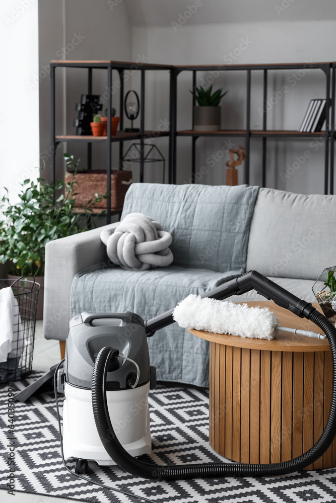 Interior of living room with sofa, table and vacuum cleaner