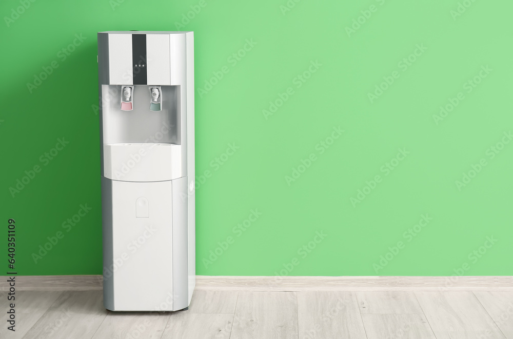 Modern water cooler near green wall