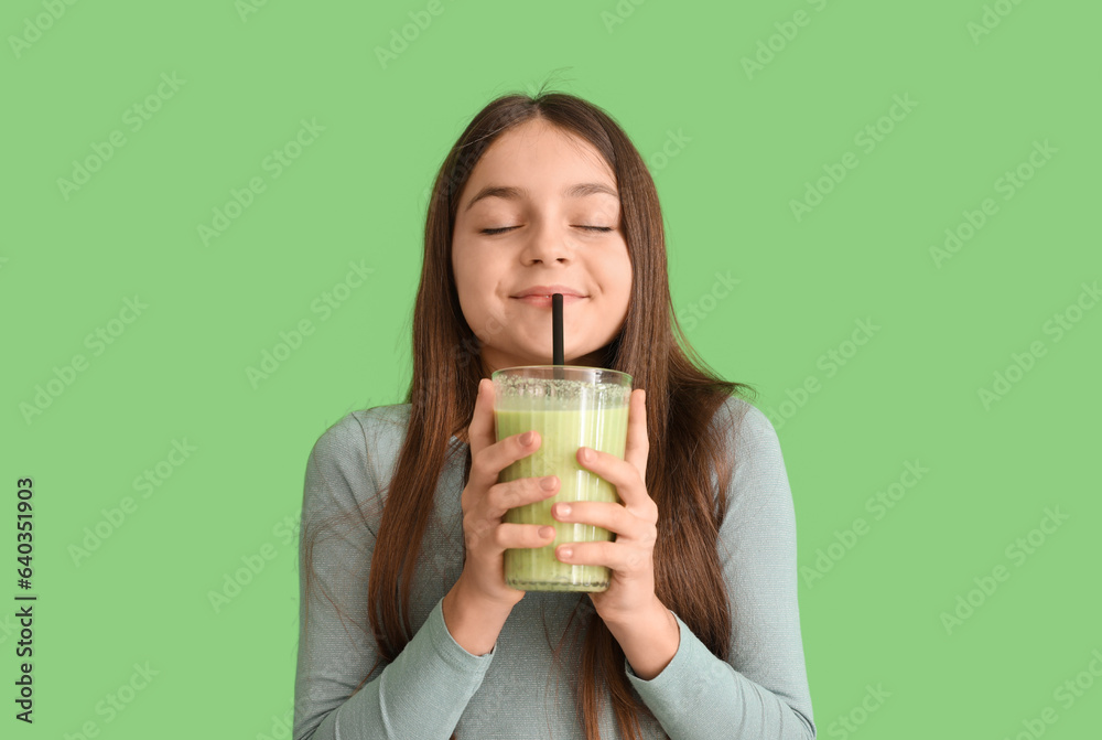 Little girl drinking smoothie on green background