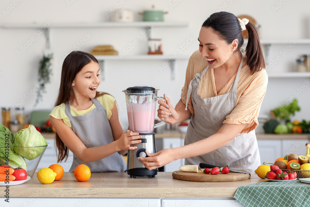 Little girl and her mother making smoothie with blender in kitchen