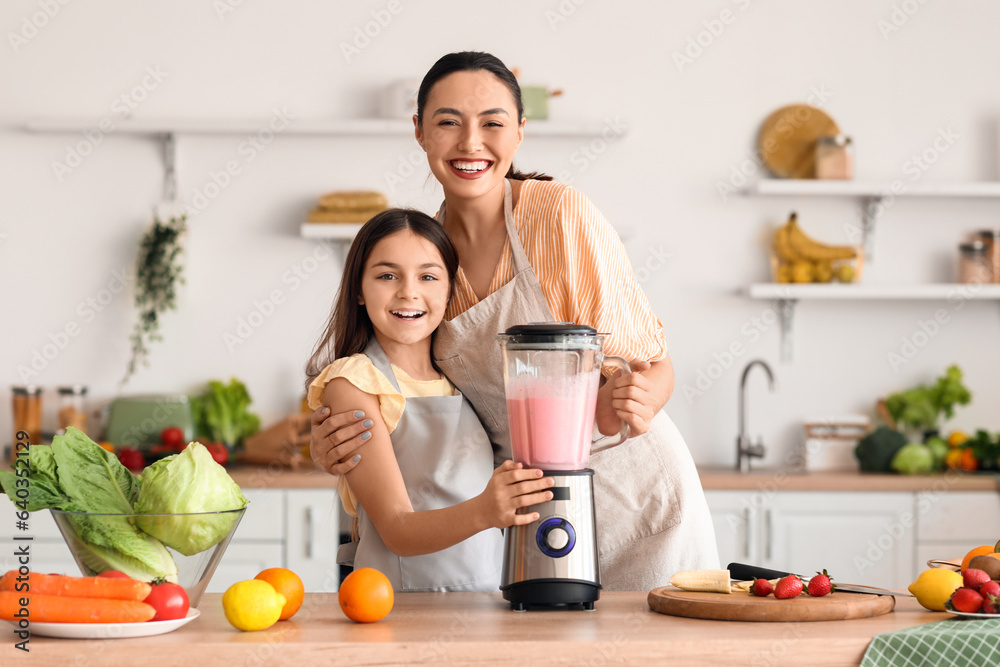 Little girl and her mother making smoothie with blender in kitchen