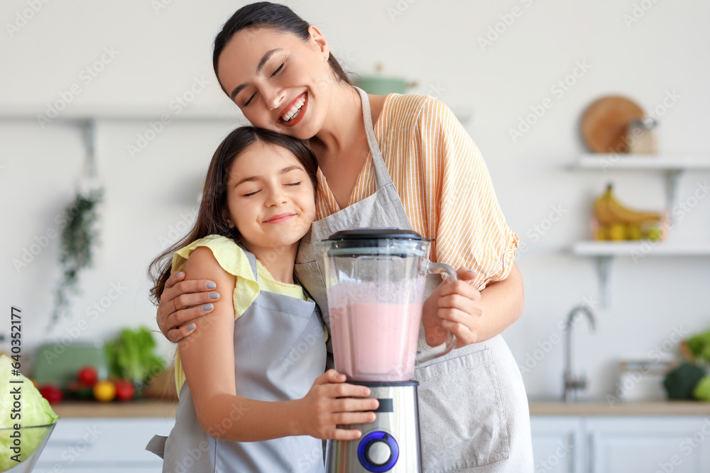 Little girl and her mother making smoothie with blender in kitchen