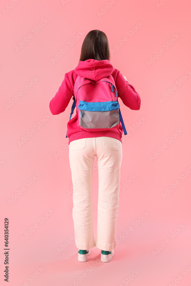 Female student with backpack on pink background, back view