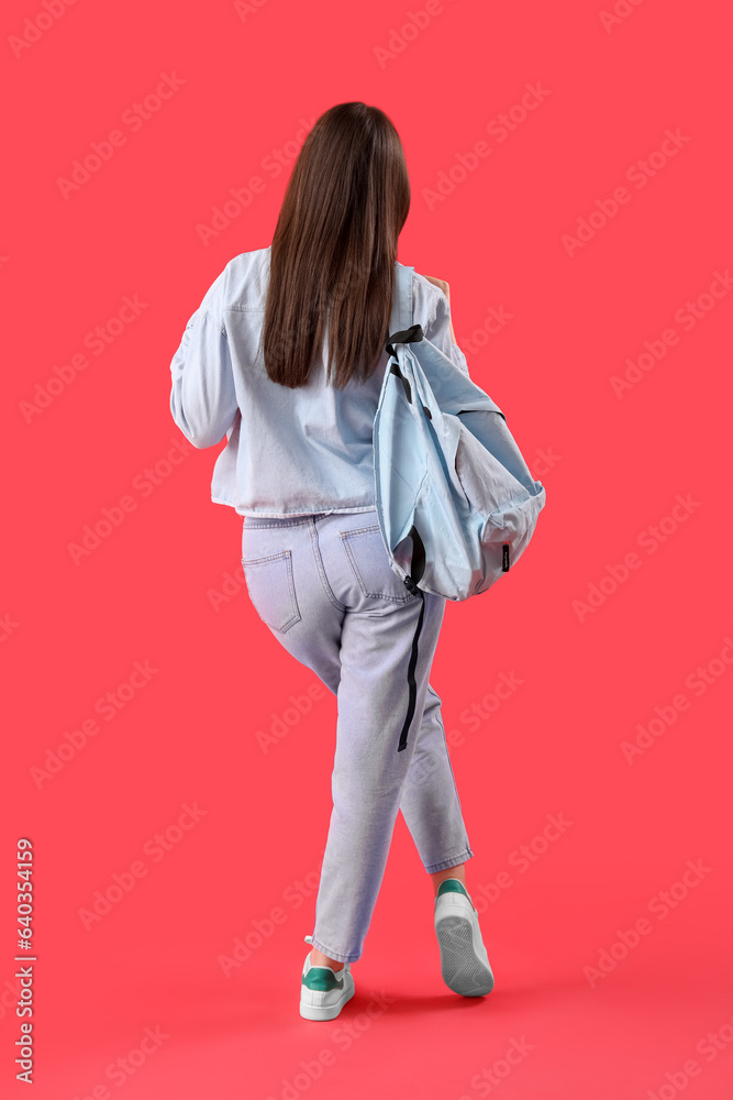 Female student with backpack on red background, back view