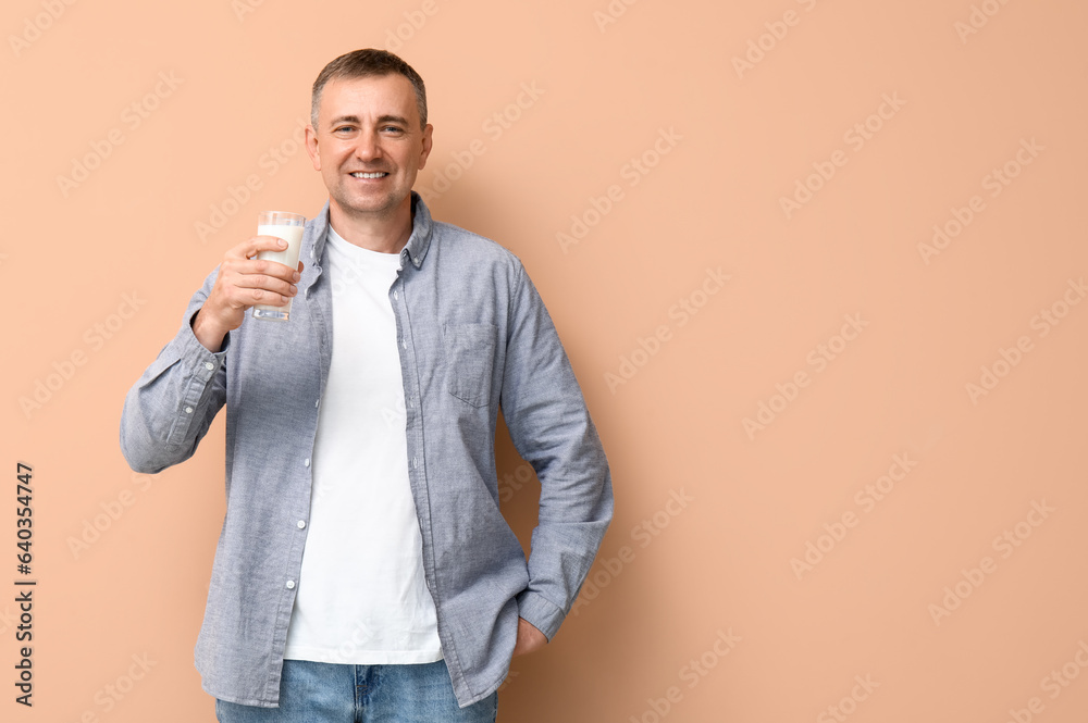 Mature man with glass of milk on beige background