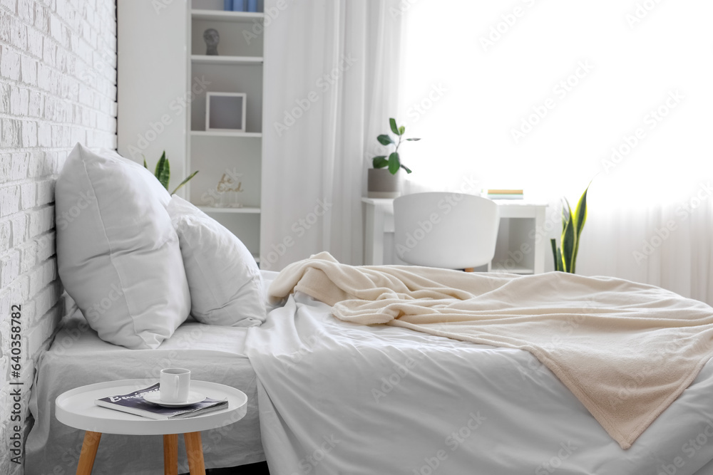 Interior of light childrens bedroom with cozy bed and desk near window