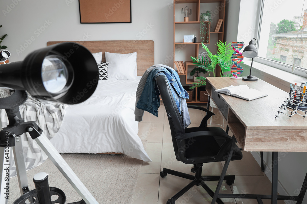 Interior of childrens bedroom with telescope, desk and cozy bed