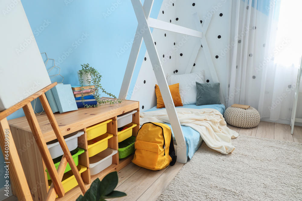 Interior of childrens bedroom with cozy bed, shelving unit and easel